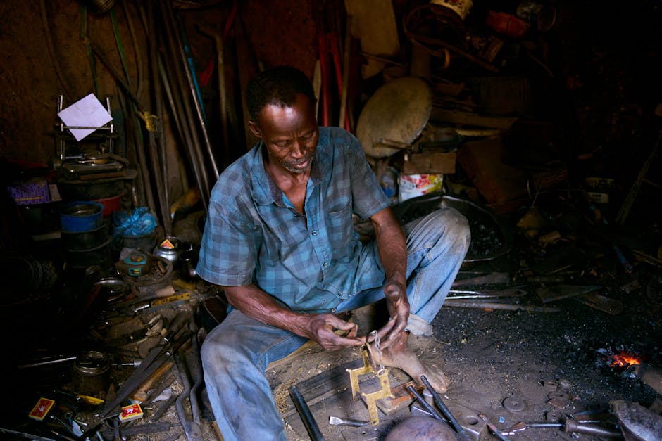 An experienced blacksmith shaping metal in a rustic workshop full of tools.