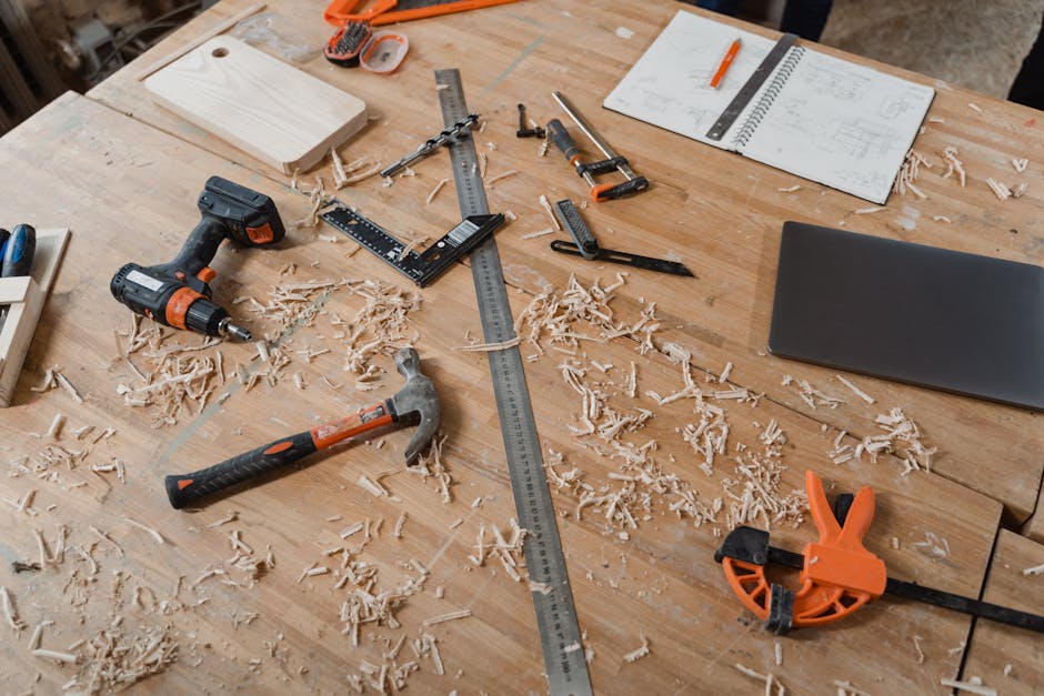 A workbench with various woodworking tools alongside sketches and wood shavings, indicating an active project.