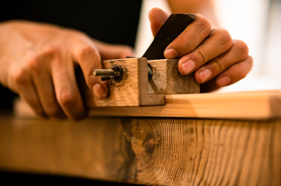 Hands meticulously adjusting a plane tool on a wooden plank, highlighting traditional woodworking.